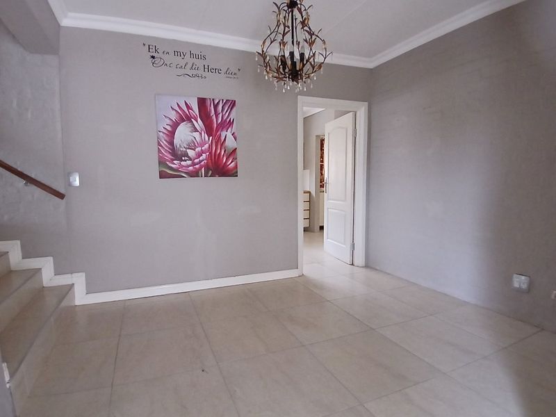 A spacious entrance hall featuring neutral tiled flooring, a staircase with a wooden handrail, and clean wall finishes.