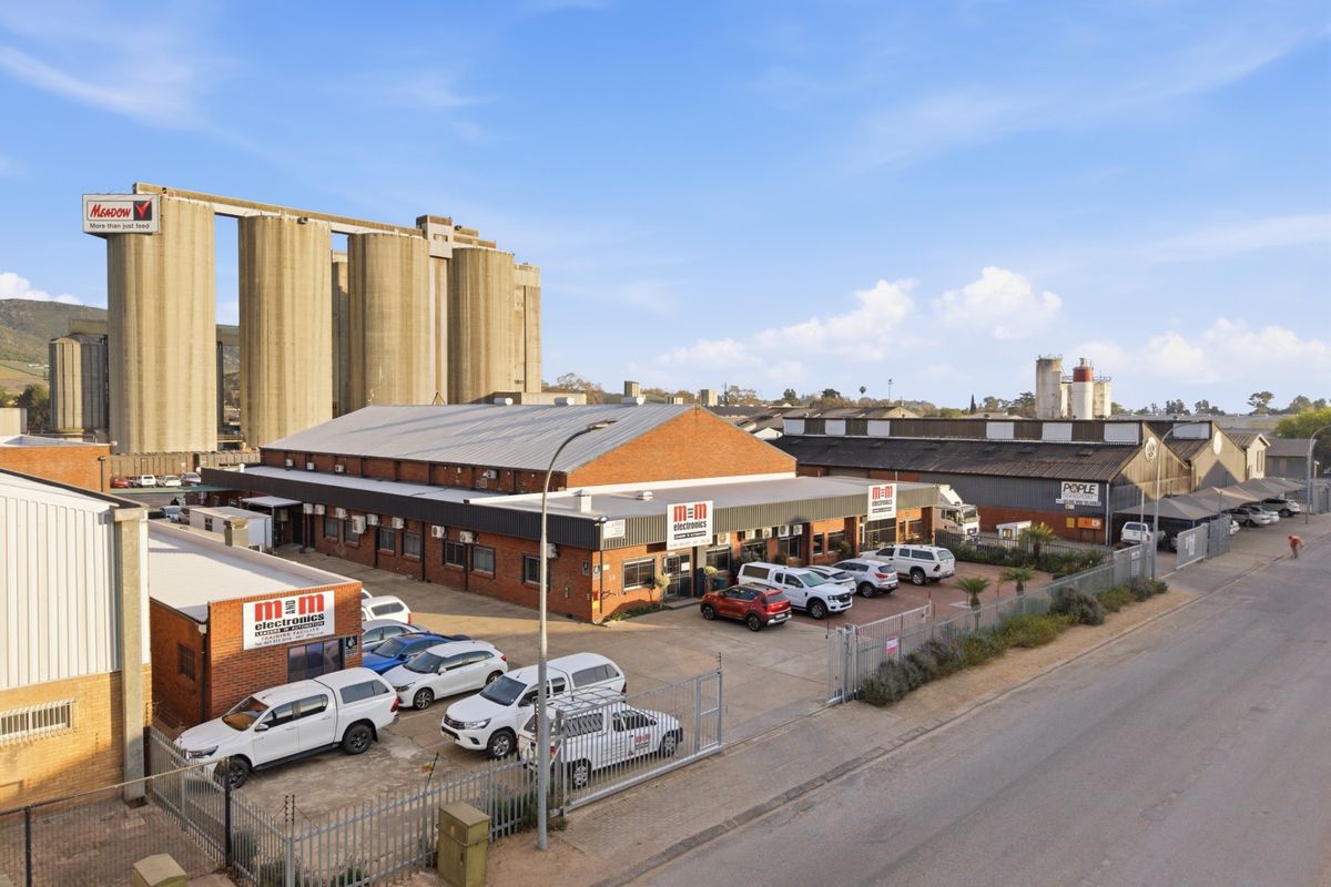 Aerial view of an industrial property featuring brick warehouse buildings, paved parking, and secure perimeter fencing in an established industrial zone.
