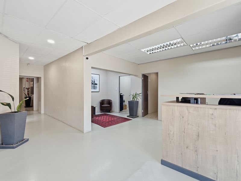 A professional industrial reception area featuring a built-in reception desk, suspended ceiling with integrated lighting, and clean, neutral finishes throughout the space.