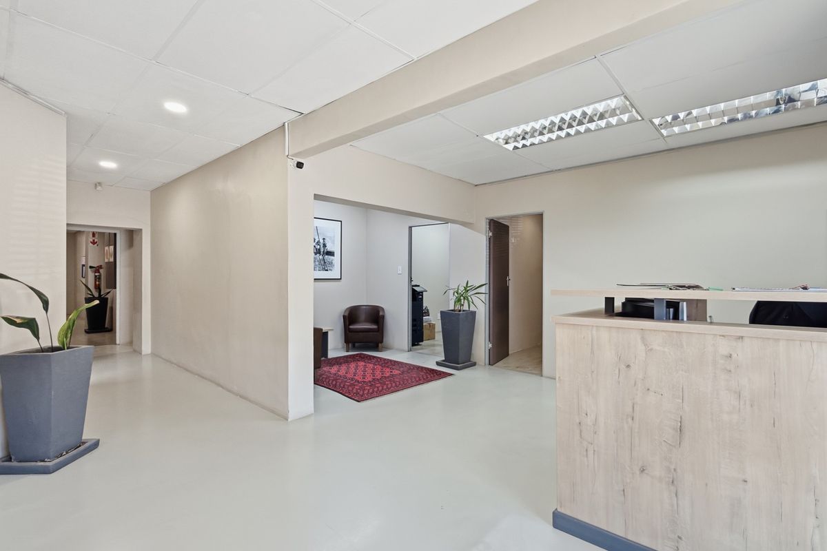 A professional industrial reception area featuring a built-in reception desk, suspended ceiling with integrated lighting, and clean, neutral finishes throughout the space.