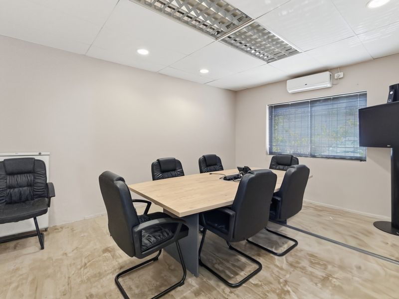 A functional office space featuring polished concrete floors, a suspended ceiling with recessed lighting, and a wall-mounted split-system air conditioner.