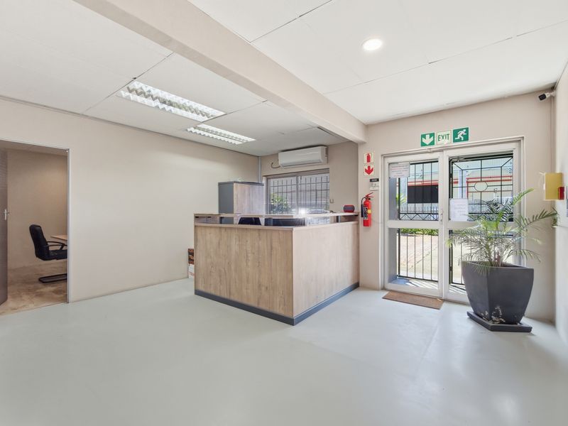 A clean industrial reception area featuring a built-in service desk, security gate, and integrated air conditioning unit.