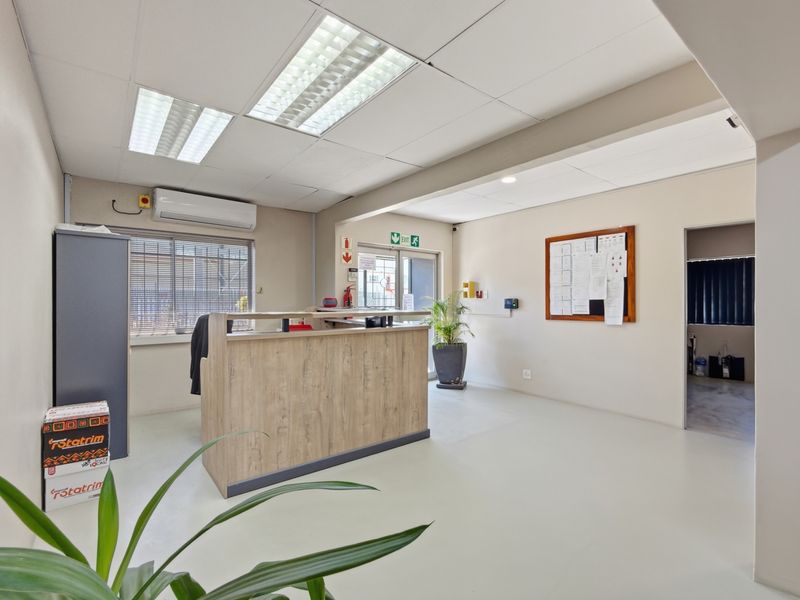 A clean and functional industrial reception area featuring a built-in service counter, suspended ceiling grid, and integrated climate control system.