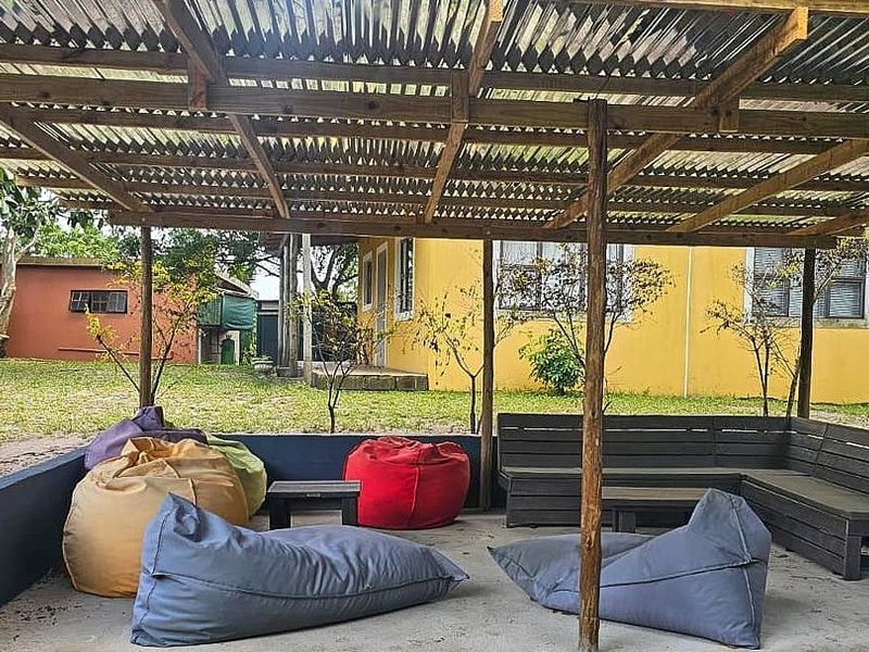A covered outdoor patio area featuring a timber pergola structure, concrete flooring, and built-in bench seating, ideal for relaxed outdoor entertaining.