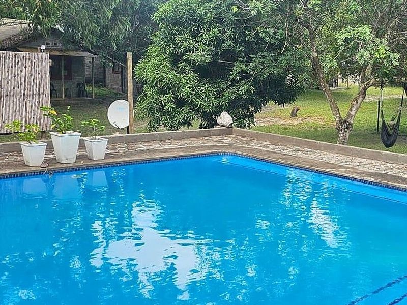 A private swimming pool set within a lush garden area, featuring stone paving and a tiled pool surround.