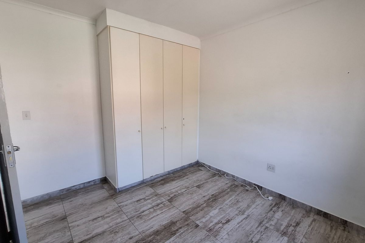 A clean, empty bedroom featuring neutral tiled flooring and built-in cupboards, providing a versatile space ready for personalization.