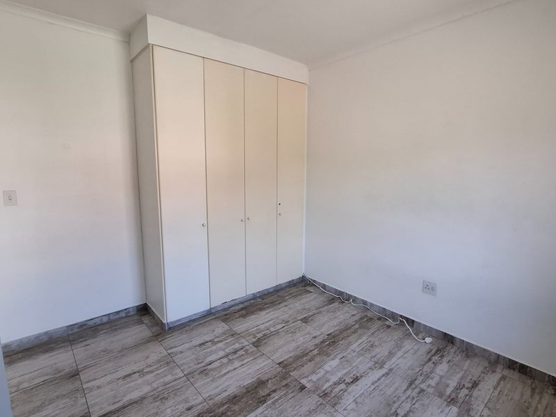 A clean, empty bedroom featuring neutral tiled flooring and built-in cupboards, providing a versatile space ready for personalization.