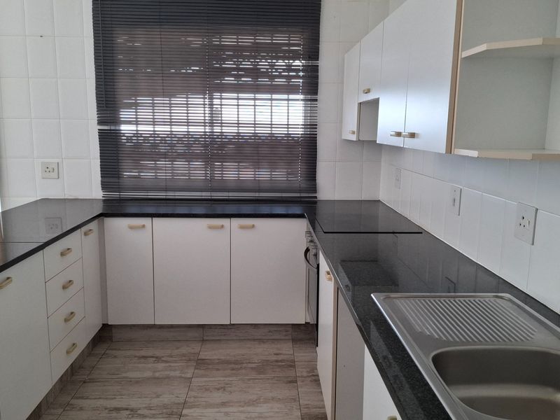 A clean, functional kitchen featuring granite countertops, white cabinetry, tiled backsplash, and a stainless steel sink, offering a neutral base for modern updates.