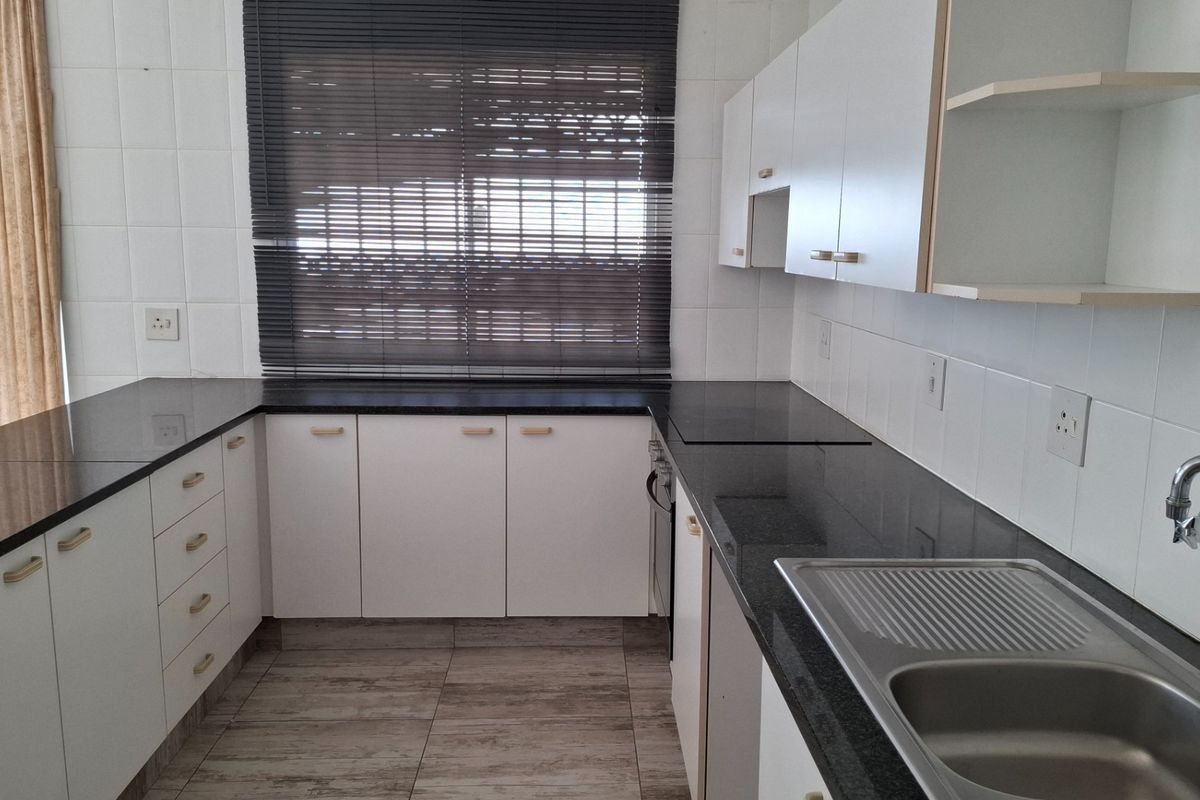 A clean, functional kitchen featuring granite countertops, white cabinetry, tiled backsplash, and a stainless steel sink, offering a neutral base for modern updates.