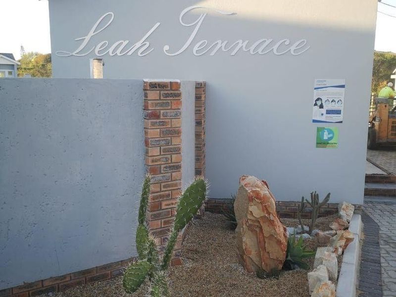 Front entrance area of Leah Terrace featuring a modern concrete and brick boundary wall with landscaped gravel garden and paved driveway access.