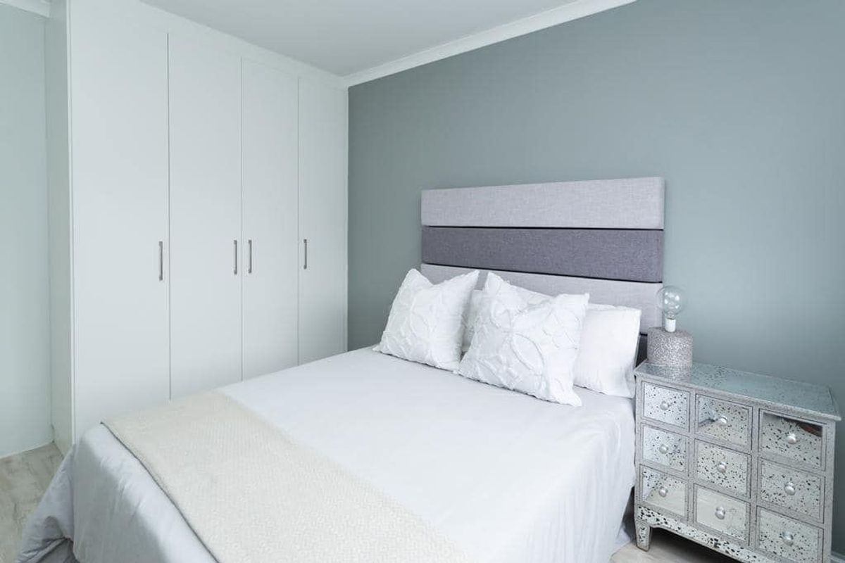 A well-maintained bedroom featuring neutral grey walls, white built-in cupboards, and decorative coving, offering a clean and modern living space.