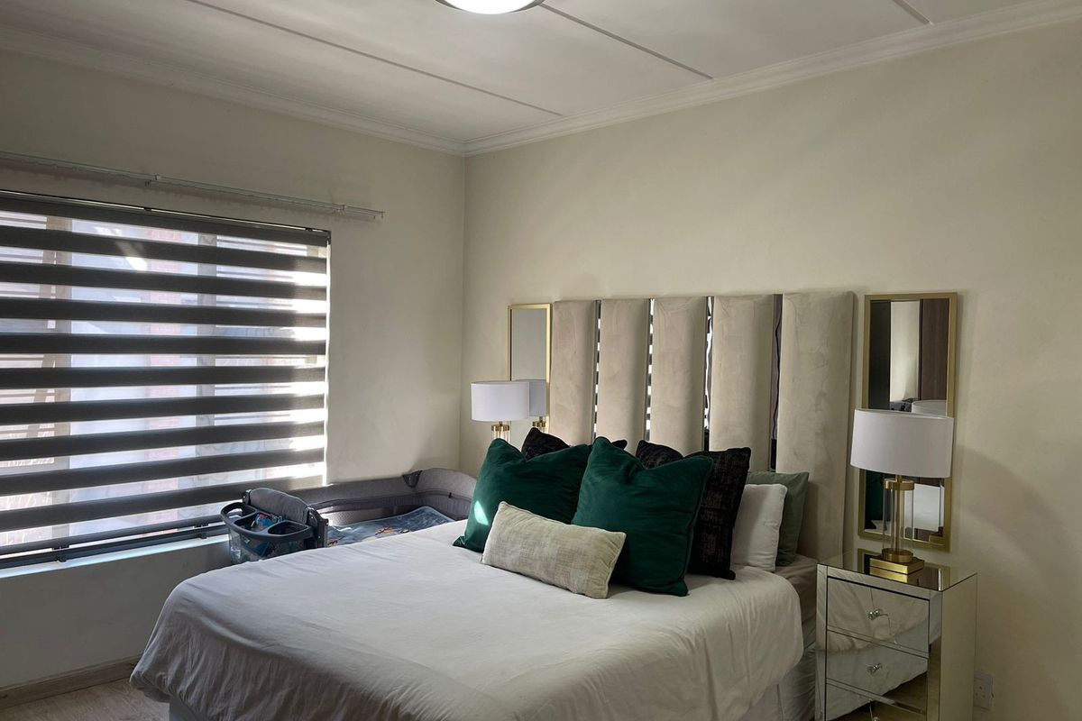 A well-maintained bedroom featuring laminate flooring, neutral wall finishes, and modern window blinds, providing a comfortable and functional living space.