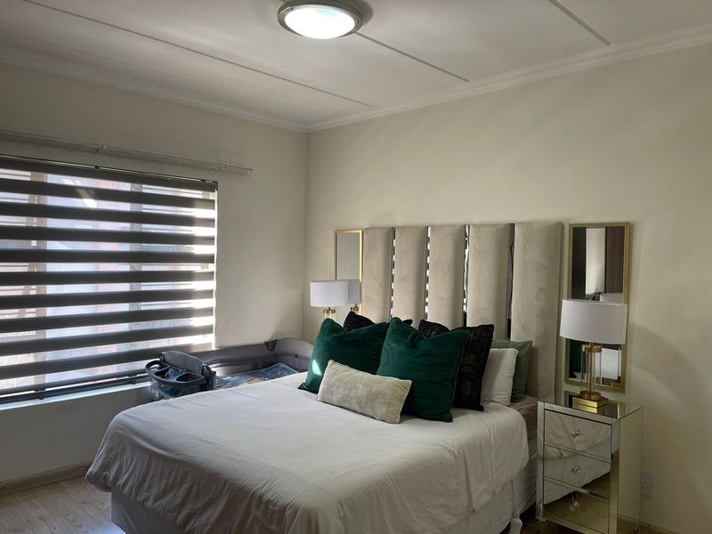 A well-maintained bedroom featuring laminate flooring, neutral wall finishes, and modern window blinds, providing a comfortable and functional living space.