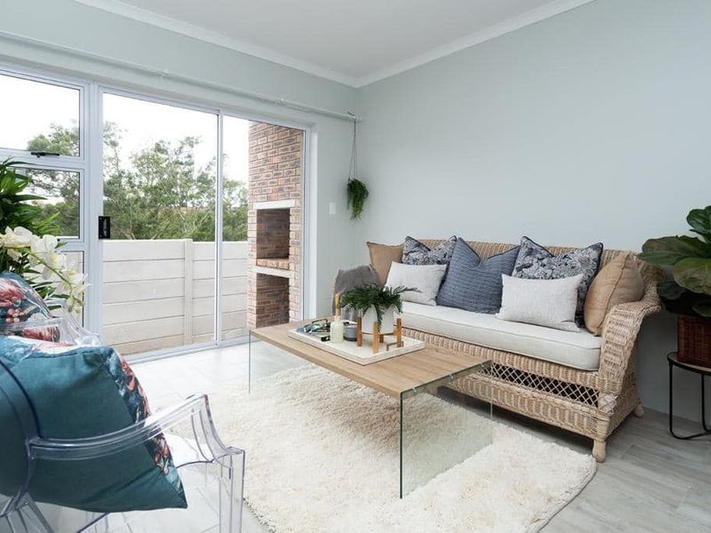 Bright living room featuring tiled flooring and a sliding glass door that opens onto a patio with a built-in brick braai.