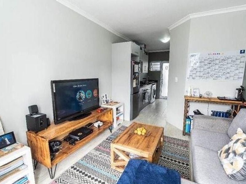 Open plan living area featuring tiled flooring and a compact kitchen space with built-in cabinetry.