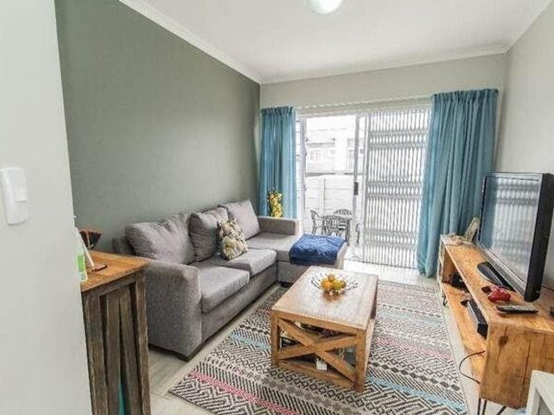A comfortable living room featuring tiled flooring, a feature wall, and a sliding glass door providing access to an outdoor patio area.