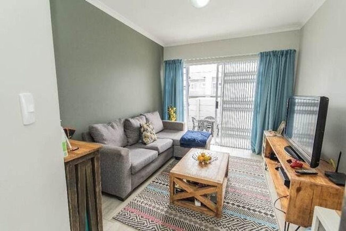 A comfortable living room featuring tiled flooring, a feature wall, and a sliding glass door providing access to an outdoor patio area.