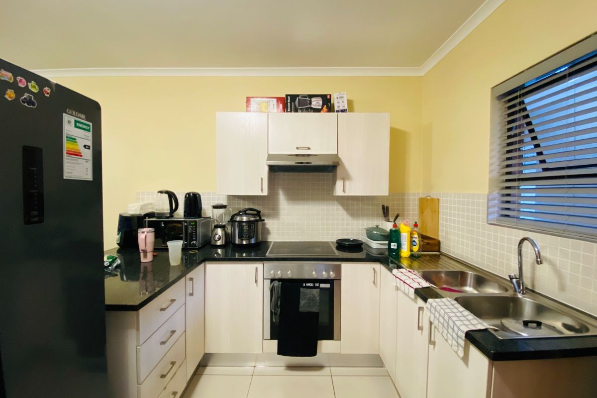 A functional kitchen featuring light-toned cabinetry, granite countertops, a tiled backsplash, and integrated stainless steel appliances including an oven and hob.