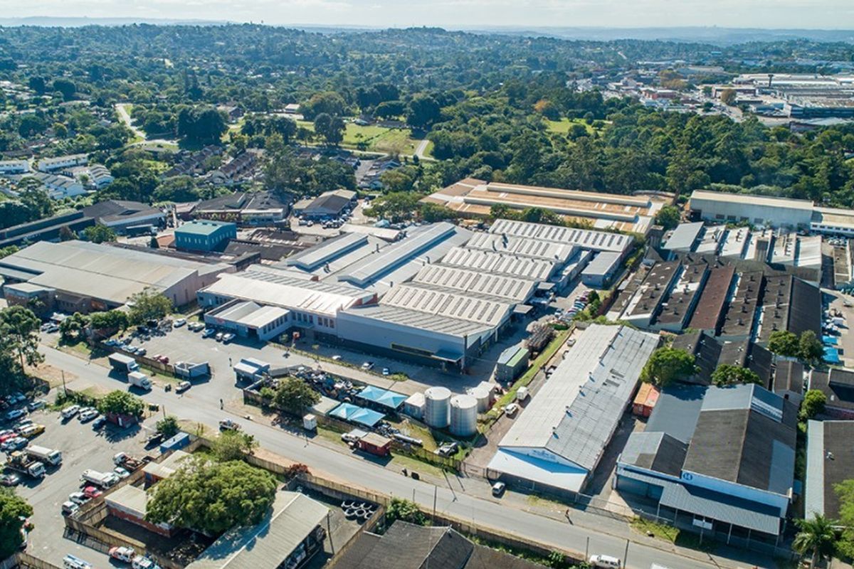 Aerial view of a large commercial industrial warehouse complex featuring multiple metal-roofed buildings, paved parking areas, and storage facilities within an urban setting.