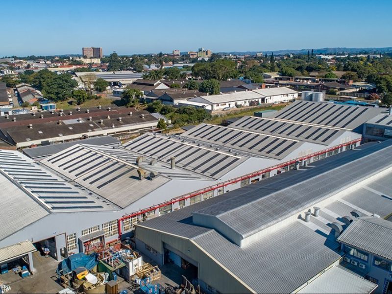 Aerial view of a large commercial industrial complex featuring extensive metal roofing, skylights, and integrated ventilation systems within an urban industrial zone.