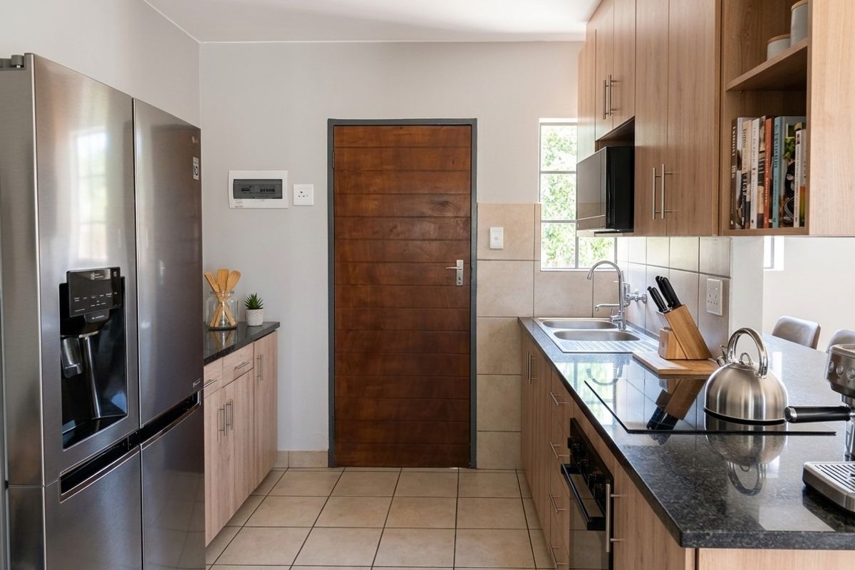 Modern kitchen featuring light wood cabinetry, granite countertops, integrated appliances, and tiled flooring, offering a clean and functional workspace.