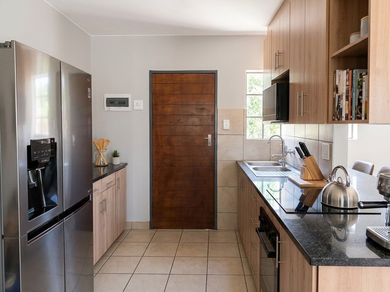 Modern kitchen featuring light wood cabinetry, granite countertops, integrated appliances, and tiled flooring, offering a clean and functional workspace.