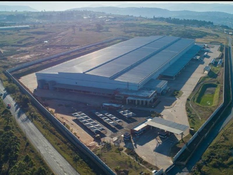 Aerial view of a large industrial warehouse facility featuring extensive paved yard space, perimeter security fencing, covered parking, and dedicated loading areas.