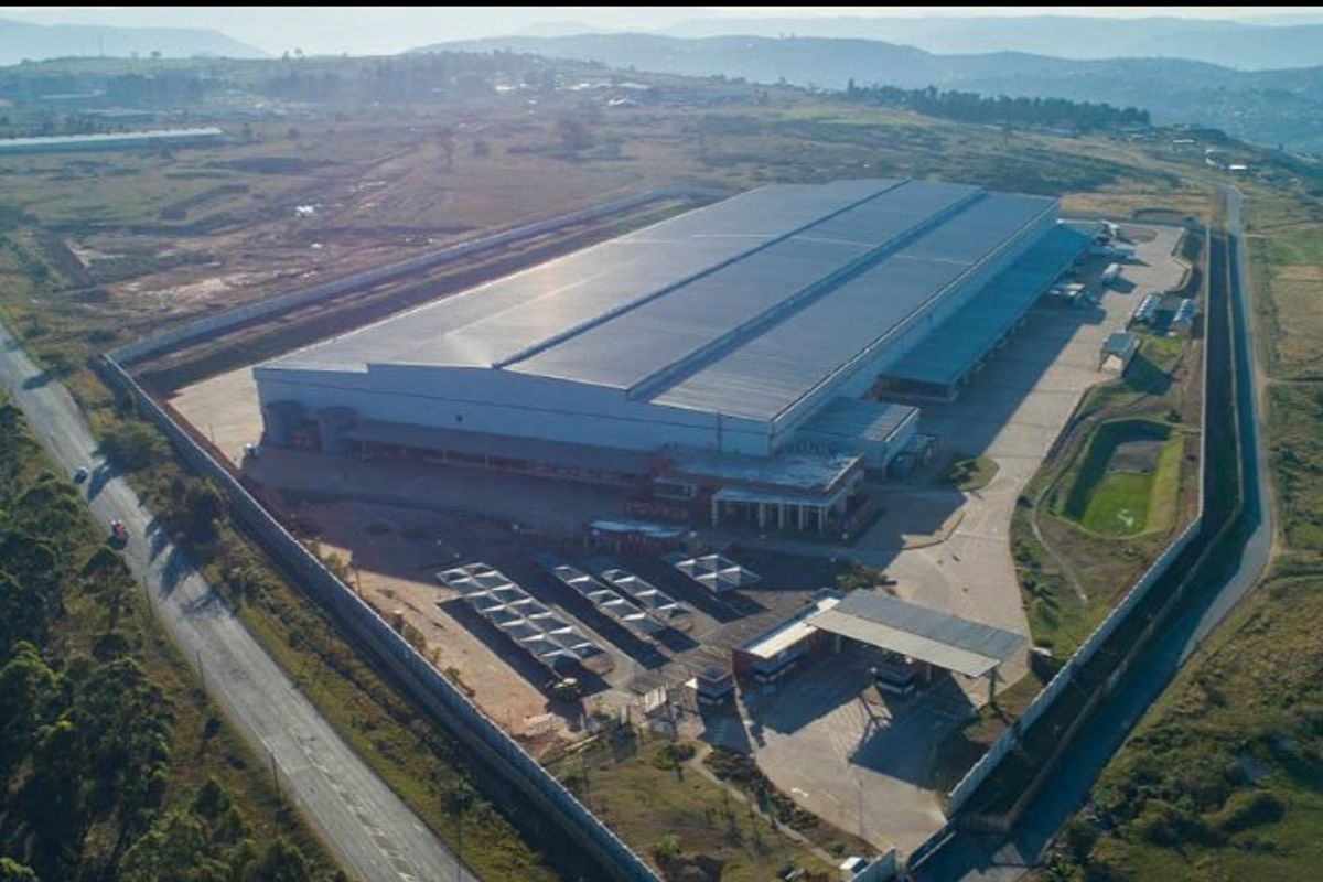 Aerial view of a large industrial warehouse facility featuring extensive paved yard space, perimeter security fencing, covered parking, and dedicated loading areas.