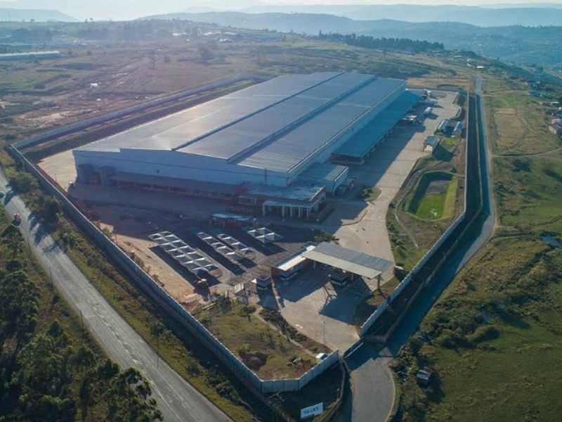 Aerial view of a large industrial warehouse facility featuring extensive paved yard space, perimeter security fencing, and a dedicated gatehouse entrance.