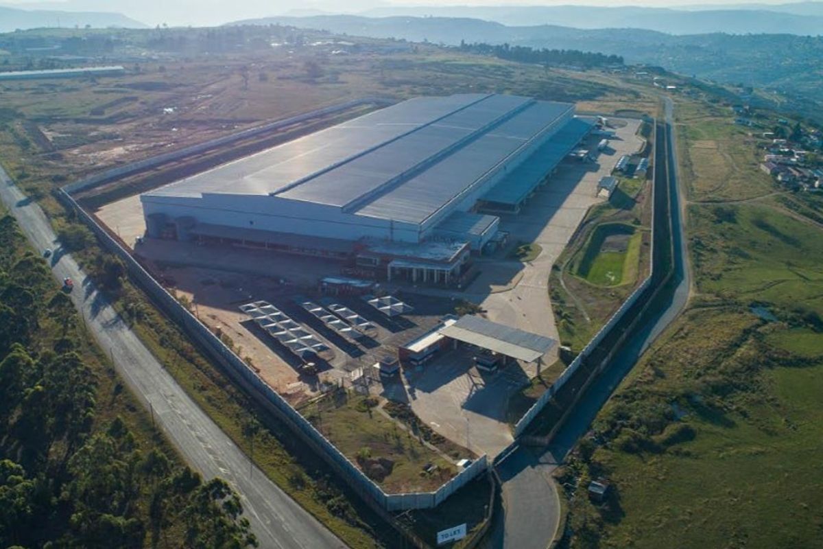 Aerial view of a large industrial warehouse facility featuring extensive paved yard space, perimeter security fencing, and a dedicated gatehouse entrance.