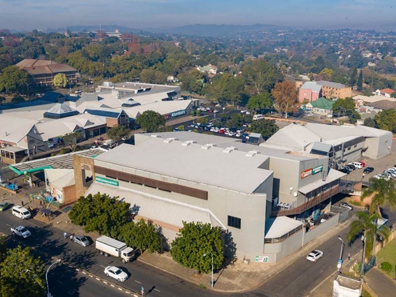 Aerial view of a commercial retail complex featuring multiple buildings, extensive parking facilities, and surrounding urban infrastructure.