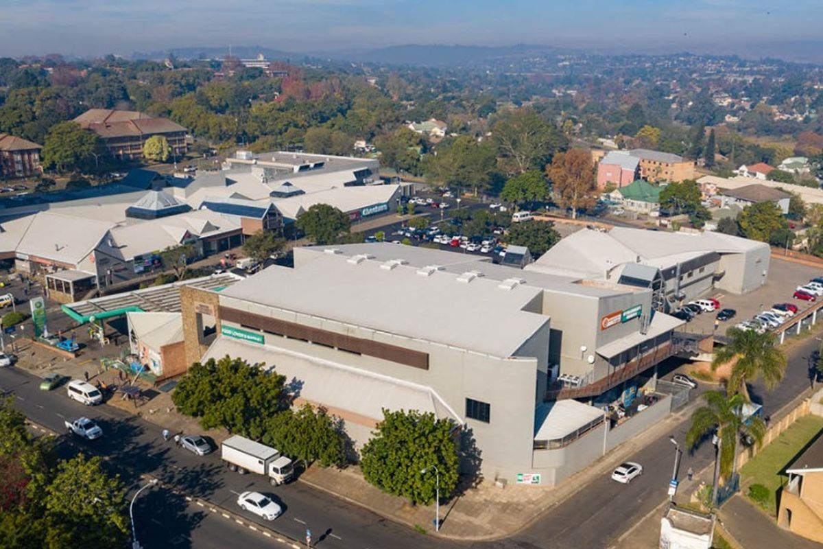 Aerial view of a commercial retail complex featuring multiple buildings, extensive parking facilities, and surrounding urban infrastructure.
