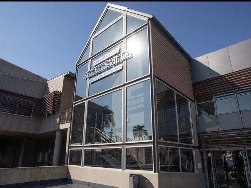 Modern retail building facade featuring extensive glass paneling, metal cladding, and architectural louvre screens, presenting a professional and contemporary commercial appearance.