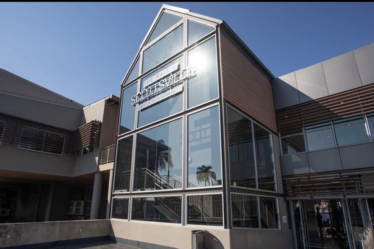 Modern retail building facade featuring extensive glass paneling, metal cladding, and architectural louvre screens, presenting a professional and contemporary commercial appearance.