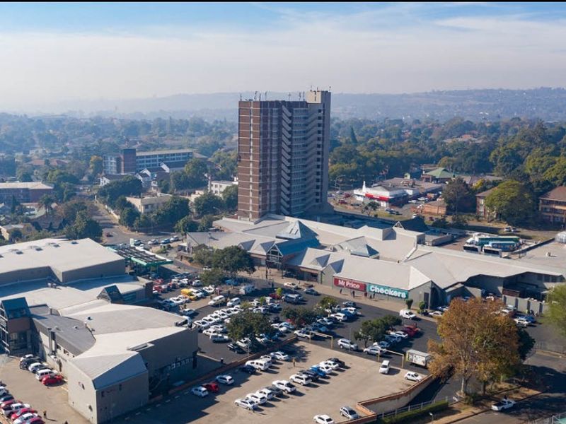 Aerial view of a retail shopping center complex featuring extensive parking facilities and surrounding urban infrastructure.