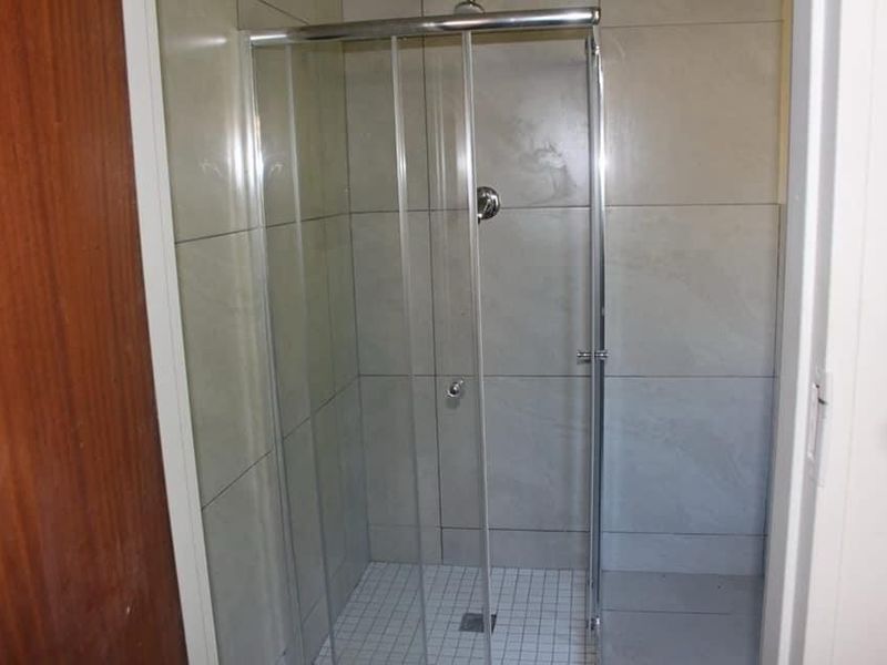 A functional shower cubicle featuring a glass enclosure, tiled walls, and mosaic floor tiling.