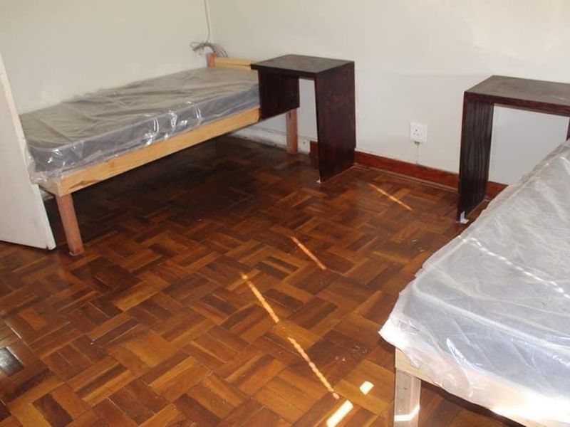 A bedroom featuring classic parquet wood flooring and neutral wall finishes, providing a functional space ready for personalization.
