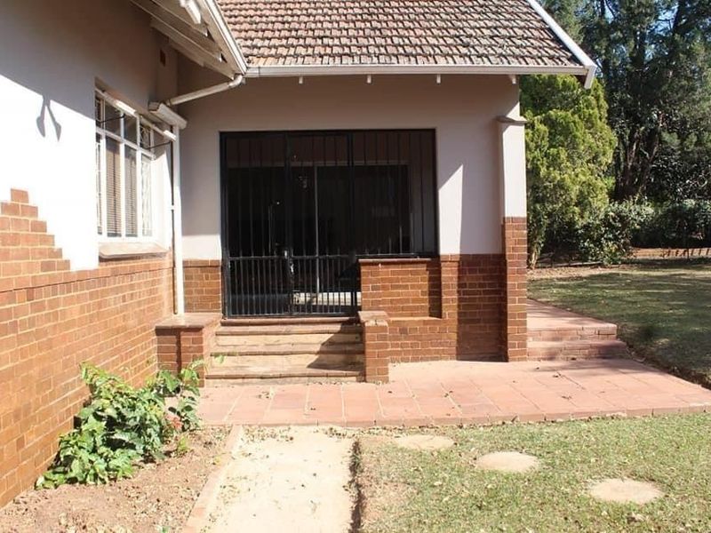 A covered brick patio area with a security gate entrance, featuring tiled flooring and direct access to the garden.