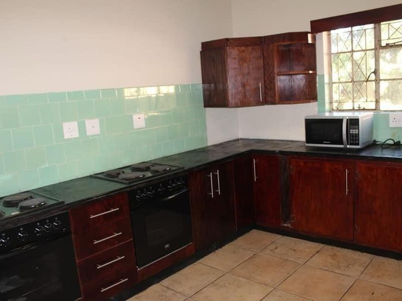 A functional kitchen featuring dark wood cabinetry, tiled backsplash, and built-in oven and hob, offering a solid foundation for a modern renovation.