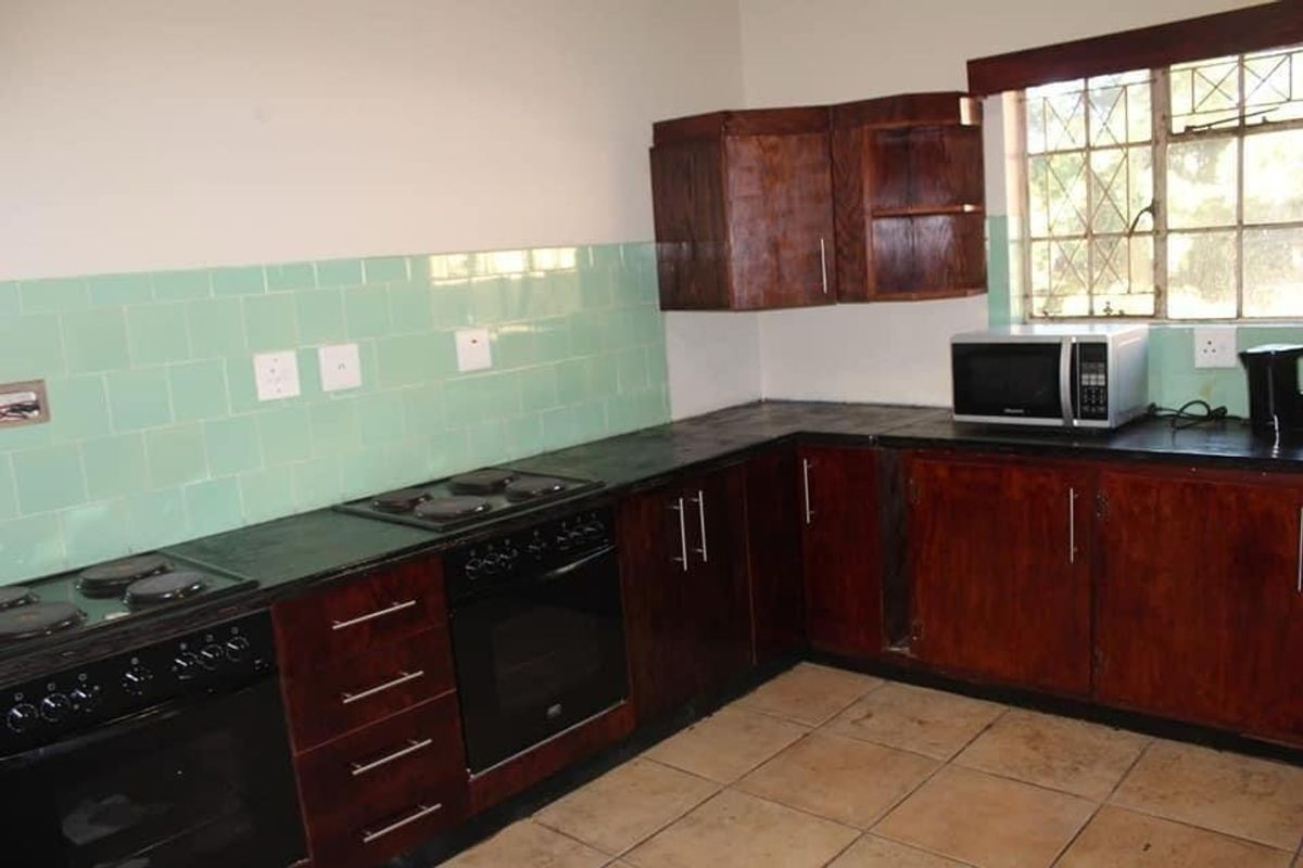 A functional kitchen featuring dark wood cabinetry, tiled backsplash, and built-in oven and hob, offering a solid foundation for a modern renovation.