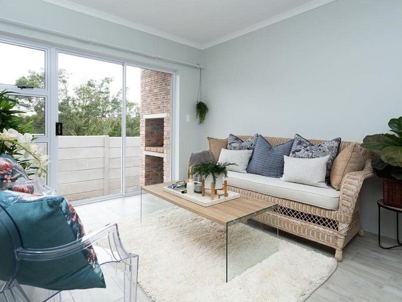 Bright living room featuring tiled flooring and a sliding glass door providing access to an outdoor area with a built-in brick braai.