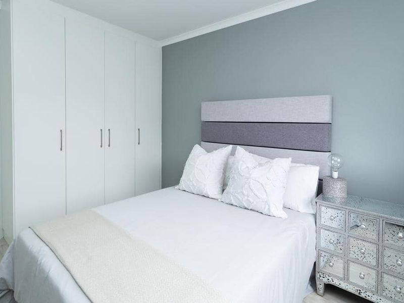 A well-maintained bedroom featuring neutral grey walls and ample built-in cupboard storage.