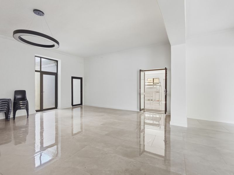 A bright, spacious, and modern office area featuring polished large-format floor tiles, a contemporary circular pendant light, and clean white walls.