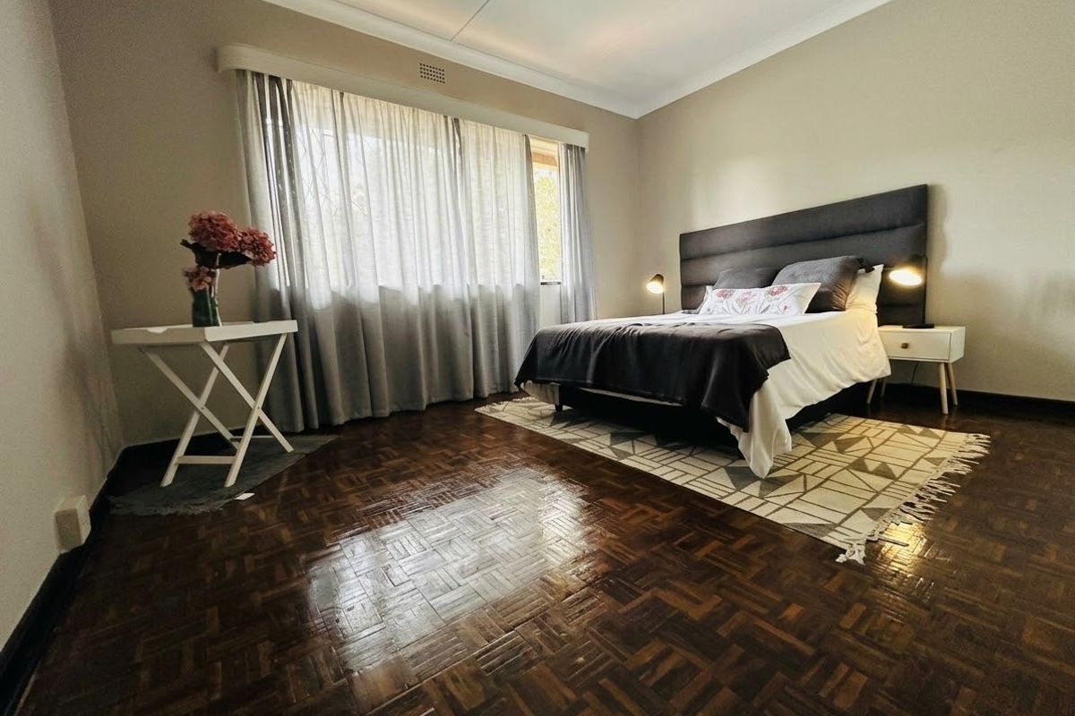 A well-maintained bedroom featuring classic parquet flooring, neutral wall tones, and a coved ceiling, offering a comfortable and inviting living space.