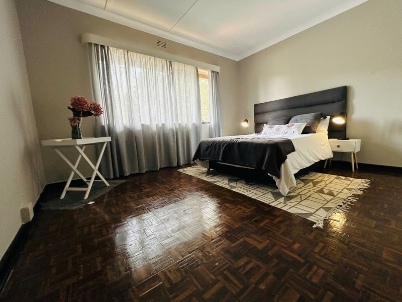 A well-maintained bedroom featuring classic parquet flooring, neutral wall tones, and a coved ceiling, offering a comfortable and inviting living space.