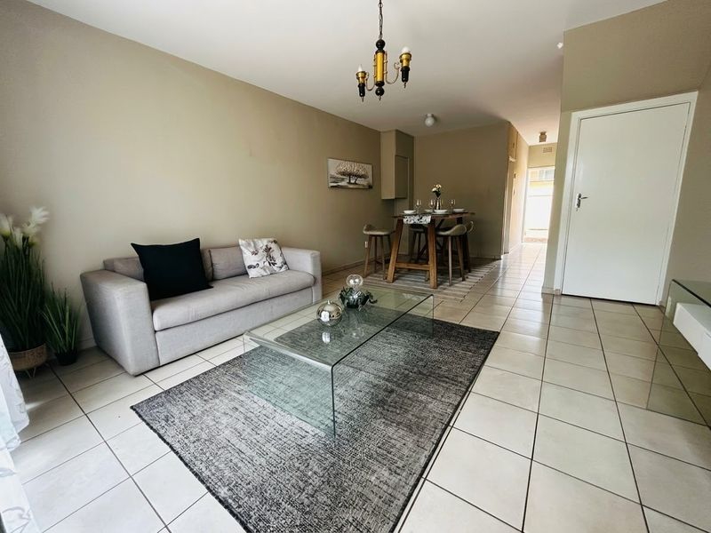 An open-plan living and dining area featuring neutral wall tones and tiled flooring, providing a functional and versatile space for daily living.