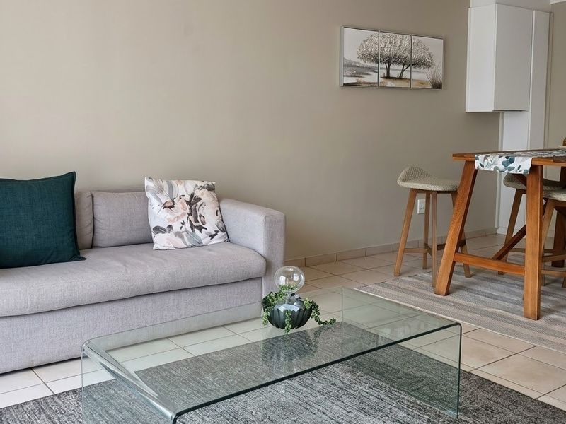 An open-plan living and dining area featuring neutral wall tones and tiled flooring, providing a versatile space for relaxation and meals.