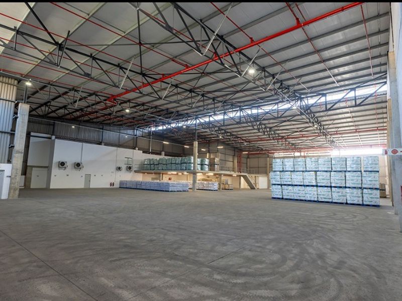 Spacious commercial warehouse featuring high-clearance steel truss roofing, polished concrete floors, integrated fire sprinkler system, and a functional mezzanine level for additional storage.