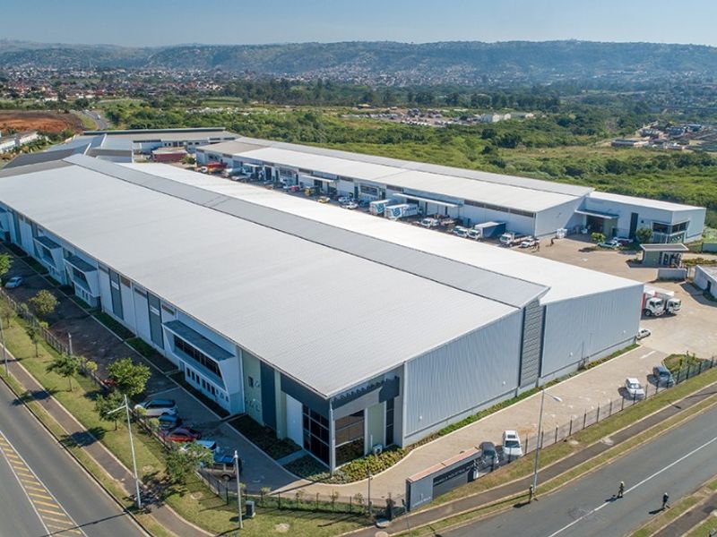 Aerial view of a large commercial industrial warehouse complex featuring extensive metal roofing, loading bays, and secure perimeter fencing.