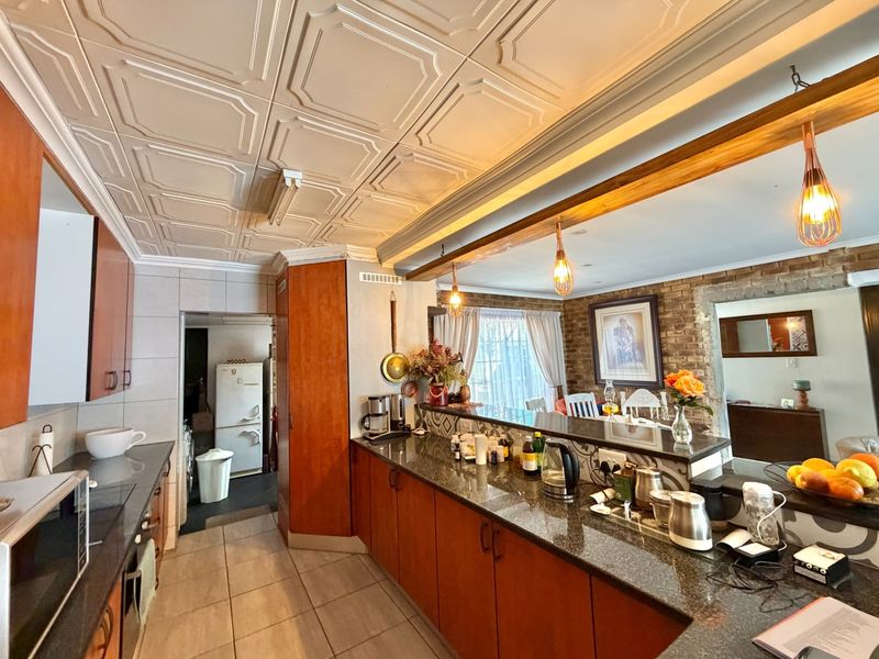 Open plan kitchen and dining area featuring granite countertops, wooden cabinetry, a breakfast bar, and a distinctive coffered ceiling with exposed brick accents.